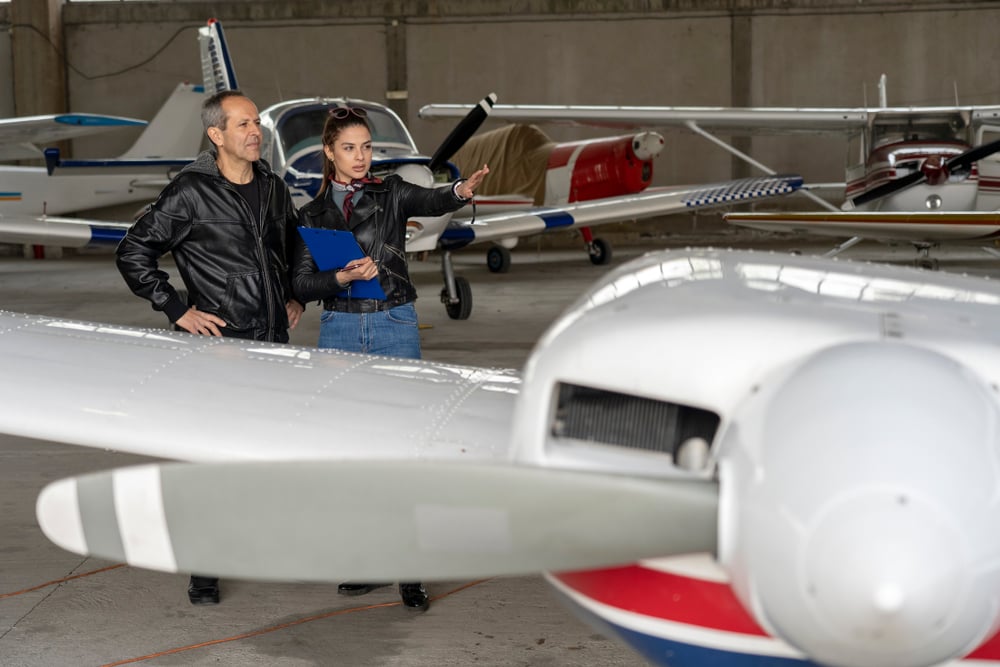 Jovem estudante e instrutor dentro de um hangar durante o curso de Pilotagem Profissional de Aeronaves