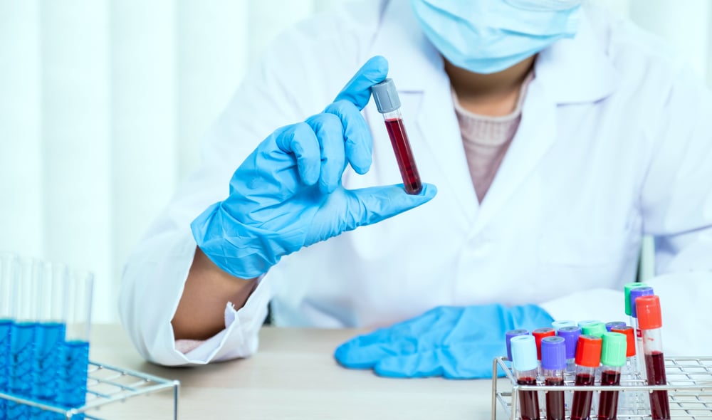 Biomédico, no exercício da profissão, segurando amostra de sangue.