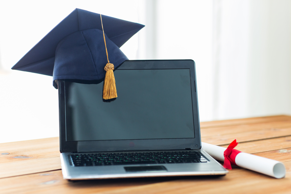 Laptop com chapéu de graduado e diploma ao lado, simbolizando que o diploma de curso EaD é reconhecido