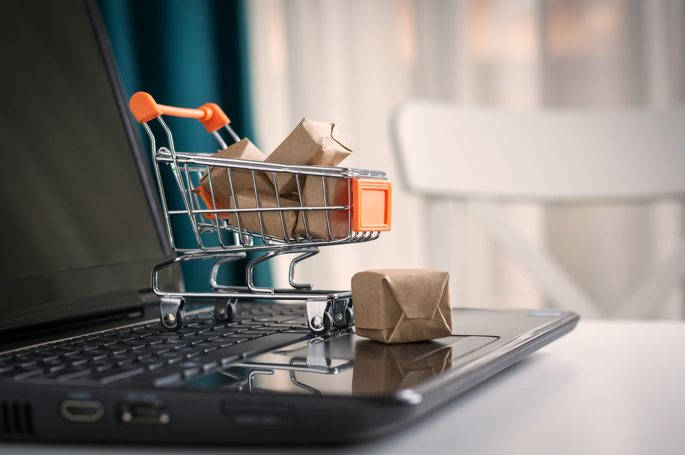 Carrinho de compras sobre laptop, simbolizando o comportamento do consumidor de forma online
